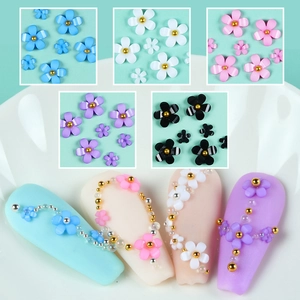 Detailed close-up of mixed size resin five-petal flowers and gold beads for nail art DIY