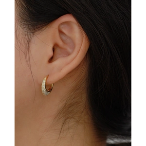 Close-up of a gold s925 silver hoop earring with paved zircon stones on model's ear