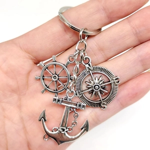 Detail of vintage silver nautical keychain featuring helm, compass, and anchor charms