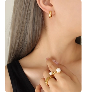 Détail de boucles d'oreilles vintage dorées 18k et bagues en perles sur modèle