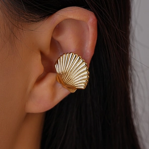 Polished gold shell ear cuff with radial texture shown on model's ear in close-up view