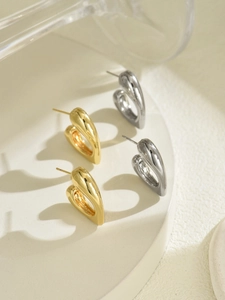 Detaillierte Ansicht goldener und silberner herzförmiger Ohrstecker auf weißem Sockel