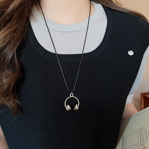 Close-up of a silver headphone pendant necklace on a model for a creative fashion look