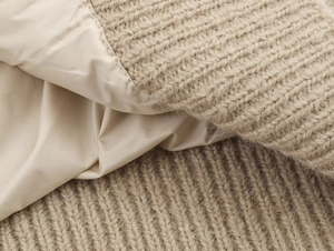 Detailed macro view of beige chunky knit fabric and smooth lining on the padded vest