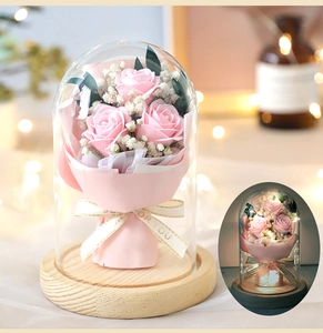 Detail of pink roses and baby's breath in glass dome with warm LED fairy lights