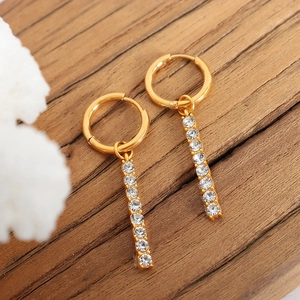 Orecchini pendenti in oro 18K con barra di zirconi su superficie in legno ruvido