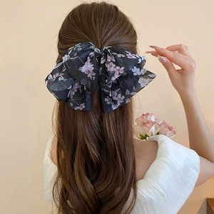 Dettaglio della molletta per capelli a fiocco in chiffon floreale su modella