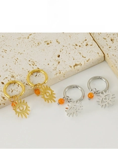 Detail of evil eye hoop earrings in gold and silver steel with orange bead accents