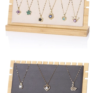 Detail view of gold necklaces with clover and swan pendants on bamboo display stand
