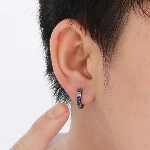 Close-up of vintage silver Cuban chain earring with grainy texture on male model