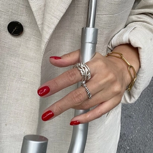 Close-up of twisted silver rings and gold paperclip chain bracelet on hand