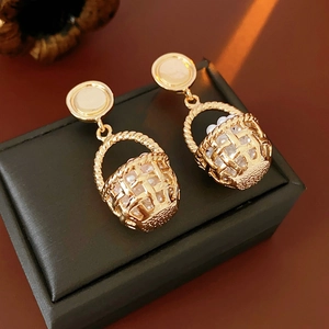 Close-up of vintage golden basket earrings with white pearls on a black jewelry box