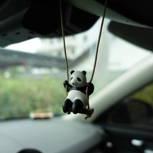Detailed view of a cute panda swinging ornament hanging from a car rearview mirror