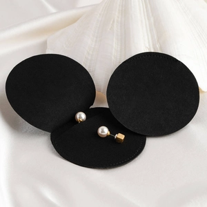 Elegant black microfiber jewelry pouch with pearl earrings on a silk and shell backdrop