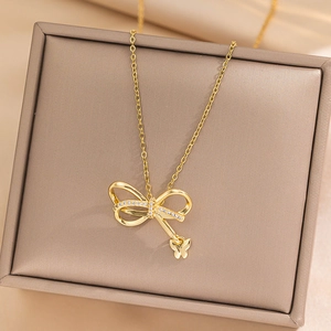 Elegant gold bow necklace with sparkling crystals and small butterfly pendant in box