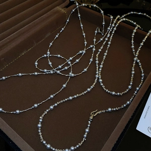 Détail d'un collier argenté multicouche avec perles dans un coffret à bijoux brun