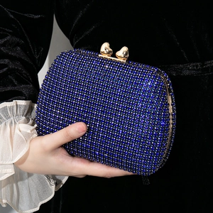 Elegant blue rhinestone evening clutch bag with golden heart clasp held by a model