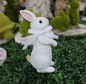 Close-up of resin rabbit with wicker texture and white silk bow for garden decor