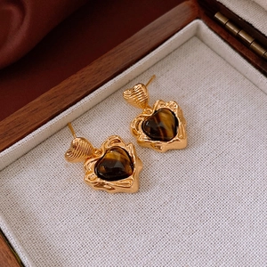 Détail de boucles d'oreilles cœur vintage plaquées or avec incrustation d'œil de tigre