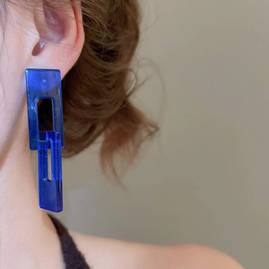 Close-up of model wearing blue geometric resin rectangle pendant earrings
