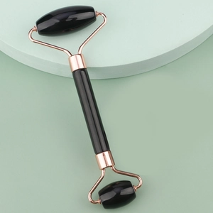 Close-up of double-headed black facial jade roller with rose gold metal frame