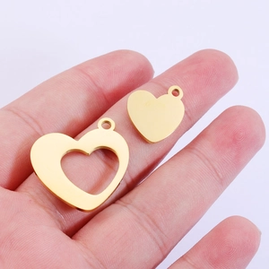 Polished gold stainless steel heart charms with solid and hollow design on a palm
