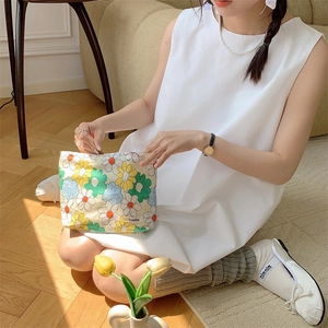 Detail of floral cotton makeup bag with daisy pattern held by a model in a sunny room