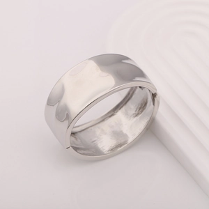 Detailed close-up of wide silver metal cuff bracelet featuring a textured hammered finish