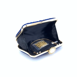 Detail view of open navy blue evening clutch with flower rhinestone clasp and chain