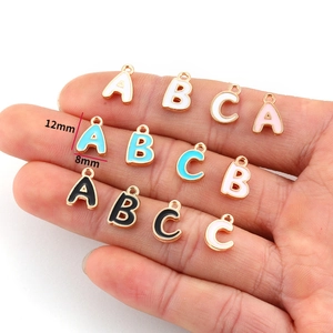 Detail of 12mm x 8mm colorful enamel alphabet pendants in gold alloy for DIY jewelry