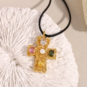 Detail of 18K gold-plated cross pendant with colorful gemstones and center pearl on coral