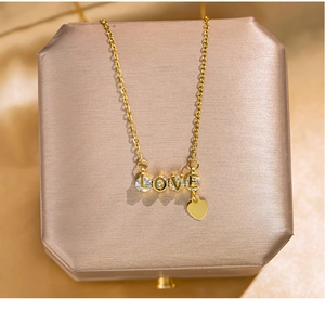 Detail of gold LOVE pendant with sparkling crystals and a heart-shaped tassel charm