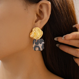 Detailed close-up of a model wearing leopard print square earrings with gold textured discs