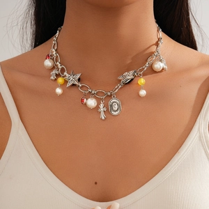 Close-up of vintage silver necklace with cross pendants, pearls and stars on a model