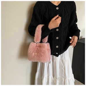 Detailed view of pink plush bucket bag with metal handle and soft faux fur texture
