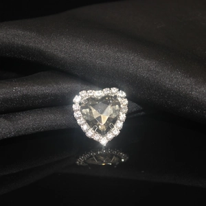 Macro shot of heart-shaped crystal with rhinestone border on black silk reflection