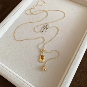 Detail of tiger eye heart pendant with gold snake chain on a white jewelry tray