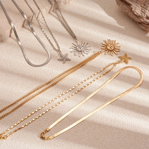 Three-layer metallic necklace set featuring sun face, starfish pendants, and snake chain
