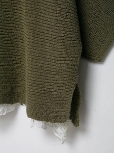 Detail of dark army green knit sweater with side slit and white lace hem trim