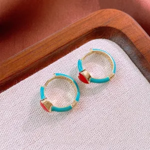 Vintage gold hoop earrings with teal enamel and red heart charms on linen background