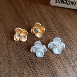 Minimalist flower stud earrings in matte gold and silver with sparkling zircon centers