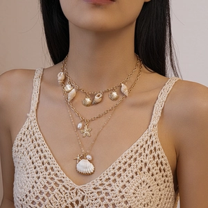 Détail du collier doré multi-rangs avec pendentifs coquillage, étoile de mer et perles