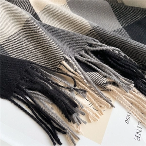 Close-up of black and grey plaid scarf fabric texture with soft tassel details