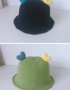 Detail of hand-knitted baby fisherman hats in black and green with heart decor