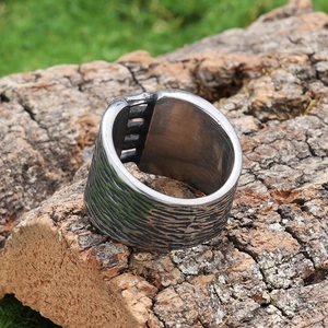 Macro detail of antique silver ring with rock texture placed on natural tree bark