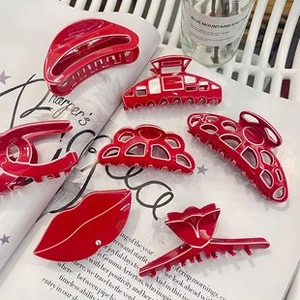 Detailed close-up of vibrant red acetate hair clips arranged on a fashion magazine