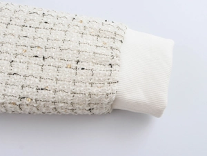 Détail de la manche en tweed à paillettes dorées avec poignet en maille côtelée crème