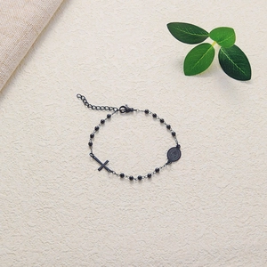 Detailed macro view of black beaded bracelet with cross pendant and religious medal charms