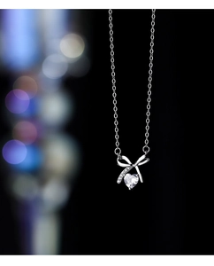 Detail of S925 sterling silver bow-knot heart pendant with sparkling zircon on cross chain