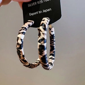 Détail de créoles en argent S925 avec texture en cuir léopard et design rond moderne